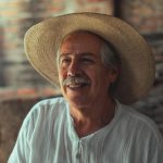 Charming portrait of an elderly man in a straw hat smiling warmly, showcasing cultural heritage.