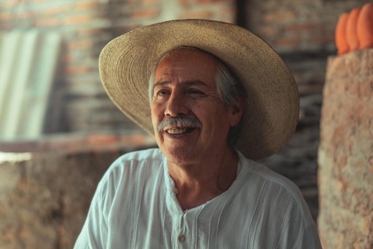 Charming portrait of an elderly man in a straw hat smiling warmly, showcasing cultural heritage.