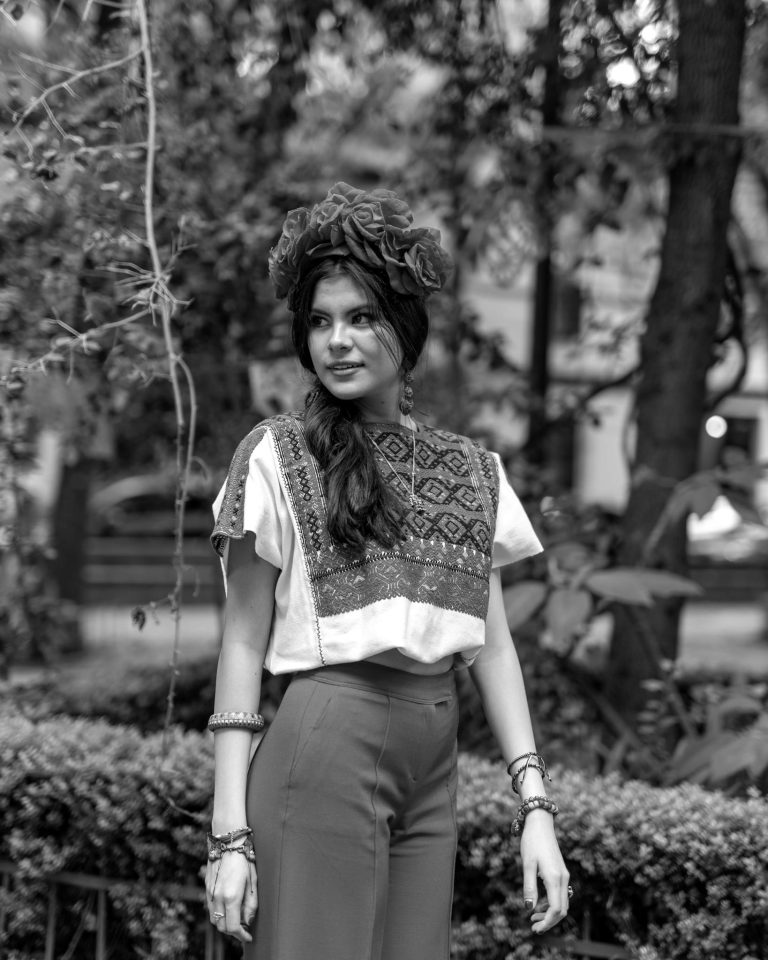 Woman in Mexican folk attire posing outdoors, embodying cultural heritage.